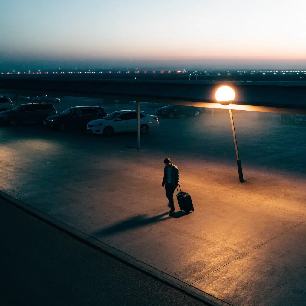 The top deck of an airport car park at dusk with a runway view beyond the roof line