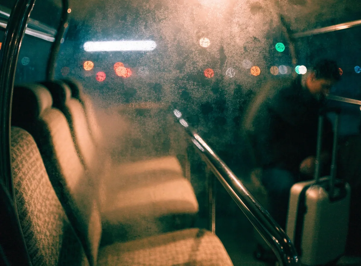 Airport shuttle interior seen through fogged glass at night with warm cabin light